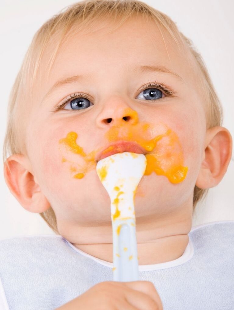 Baby mit verschmiertem Mund macht erste eigene Esserfahrungen