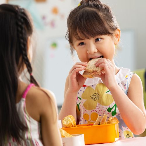 Mädchen isst ihr Pausenbrot aus ihrer Brotbox