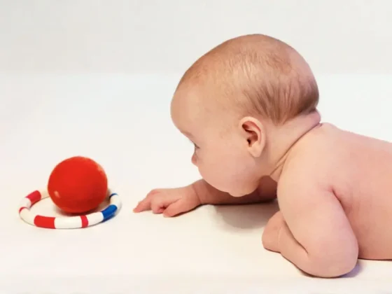 Baby in Bauchlage, fokussiert auf ein Spielzeug: Szene eines PEKiP Kurses