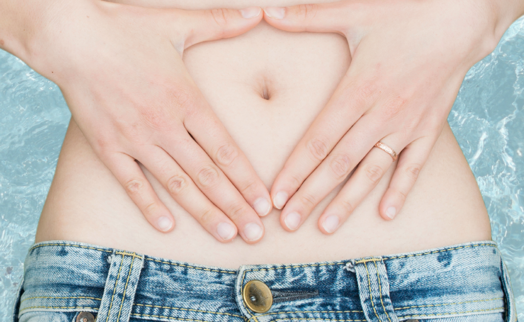Frau hält ihre Hände auf ihren Bauch - Symbolbild für eine gesunde Verdauung